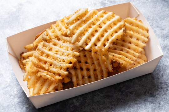 A pile of golden Crisscut French Fries with crinkle-cut lattice-pattern texture and crisp ridged surface on a white background.