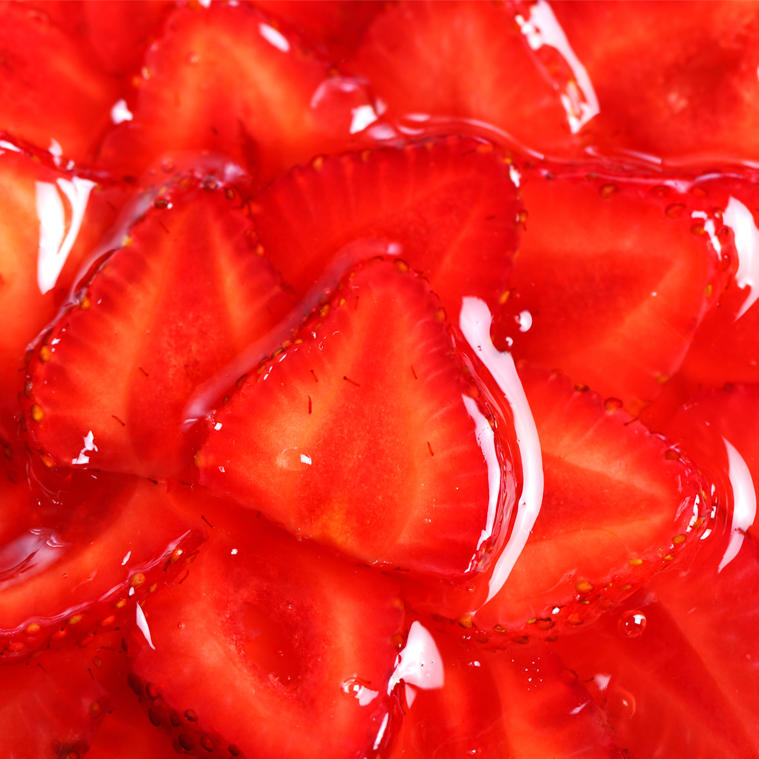 A pile of bright red Frozen Sliced Strawberries in glossy syrup with crescent wedge shape on a white background.