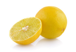 A whole yellow Sweet Lime (Mosambi) sitting next to a half-cut Sweet Lime, revealing a pale green, juicy, and seeded interior on a clean white background.